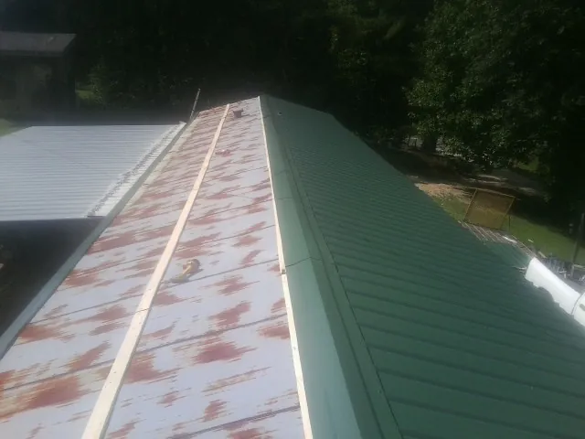 Old rusted panels beside newly installed green metal roofing — Wind Damage Roof Repair by Roofing Brothers in Prairie Village