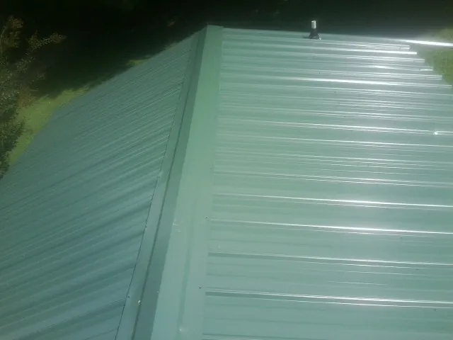 New green metal panels meeting at the ridge of a roof — Flat Roof Repair work by our crew in Prairie Village