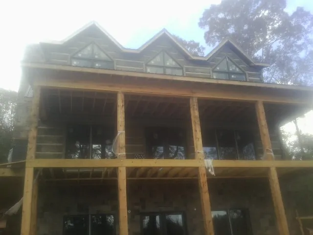 Dormers and porch framing on a large log home under construction — Roof Coating work by our crew in Prairie Village
