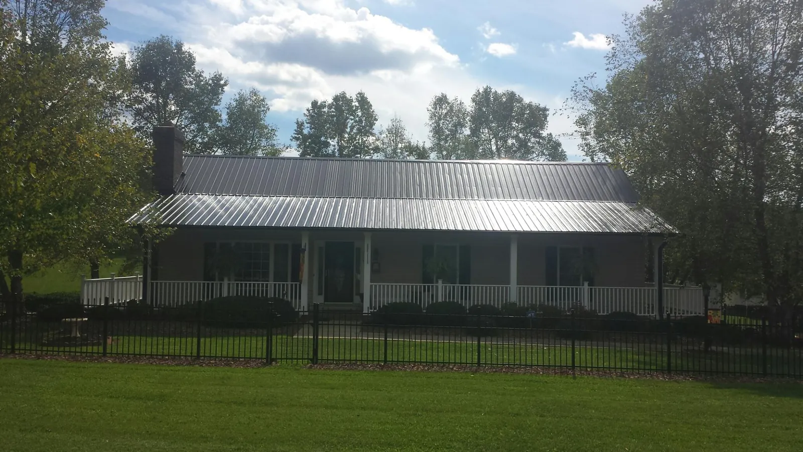 Gray metal roof on a brick ranch with a full width front porch — Gutter Guard Installation work by our crew in Prairie Village