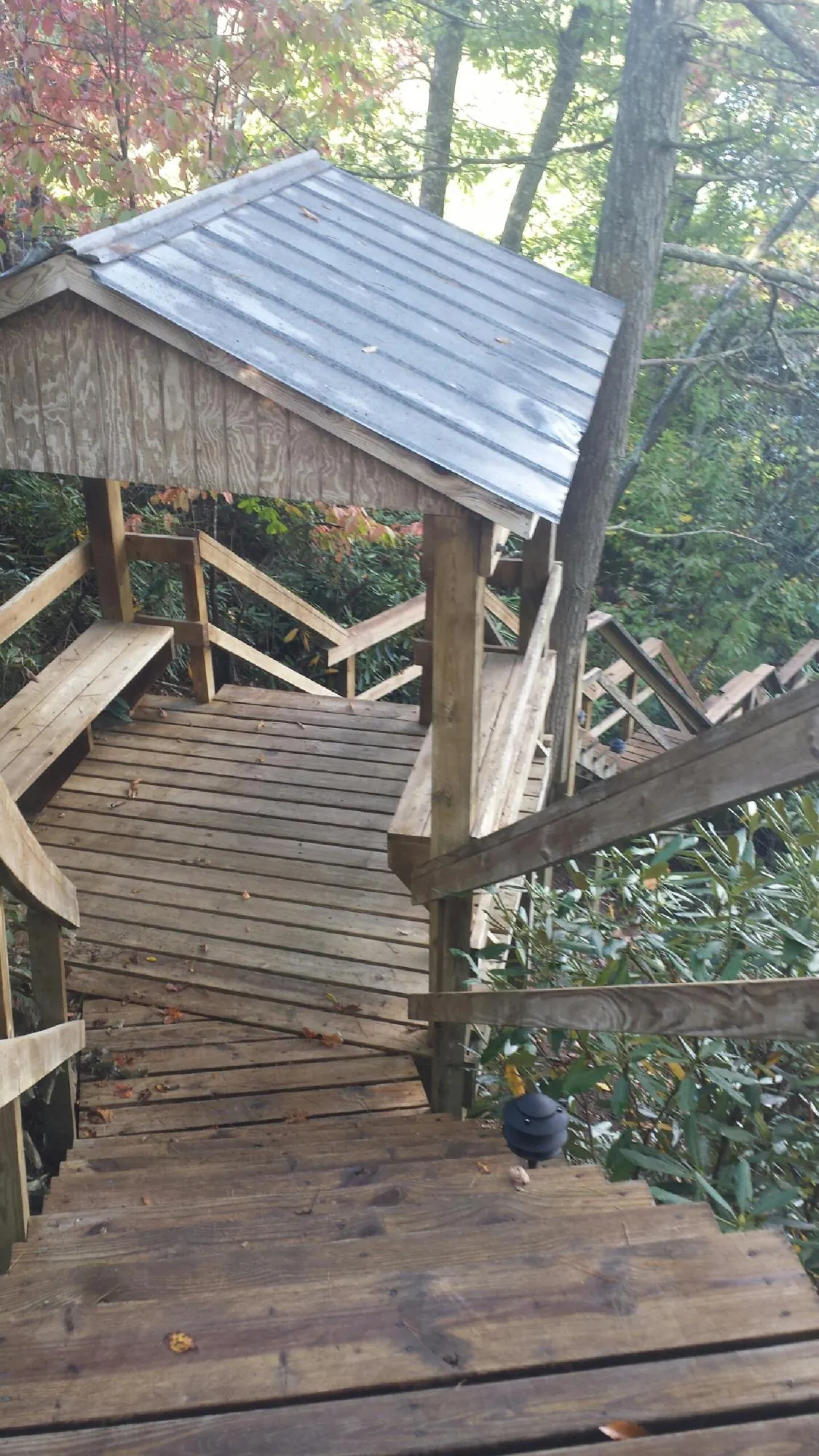 Metal roofed shelter over wooden steps on a wooded walkway — Skylight Repair & Installation work by our crew in Prairie Village