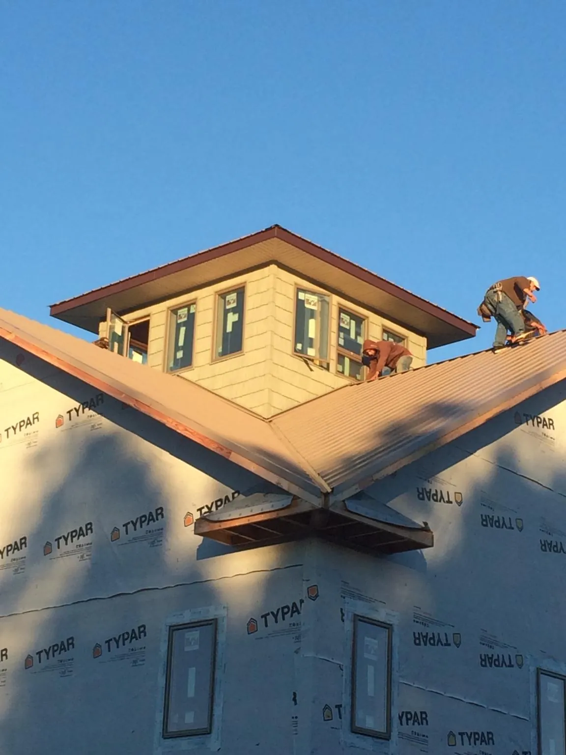Roofers working around a rooftop cupola on a new metal roof at sunset — Roof Waterproofing in Prairie Village by Roofing Brothers